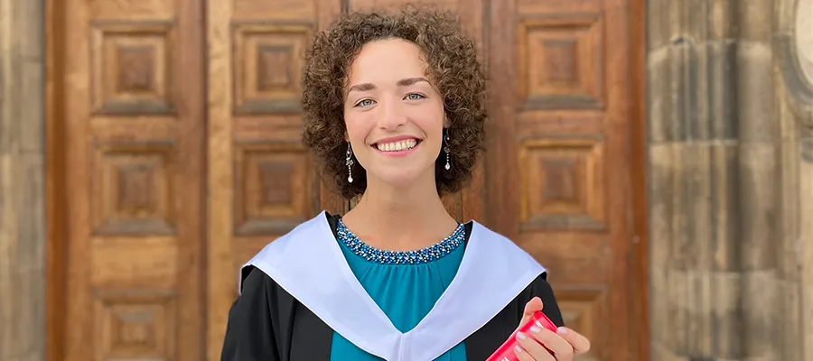 Woman in graduation robe standing outside door