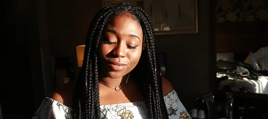 Black woman closing her eyes in a dark room. 