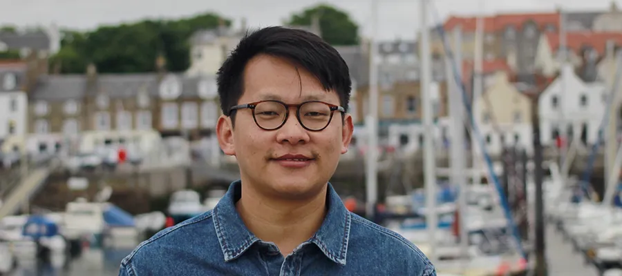 Man standing in front of a harbour, looking straight to camera.
